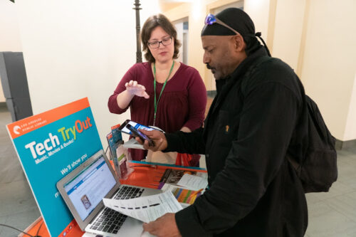 library staff member assisting a patron at a computer station